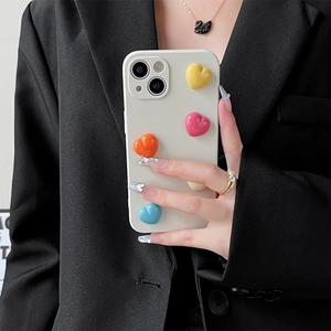 Vista dettagliata della cover iPhone crema con quattro cuori 3D colorati su sfondo di abito