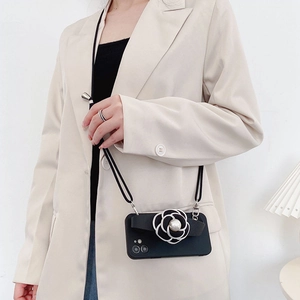 Detail of crossbody phone case featuring camellia pearl charm and adjustable strap