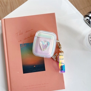 Close-up of laser holographic heart case for AirPods with matching lanyard on a book