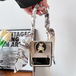 Detail of Galaxy Z Flip case featuring a golden bear relief and silk ribbon handle