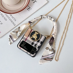 Detail of Galaxy Z Flip case with black plaid pattern, gold bear charm, and silk ribbon
