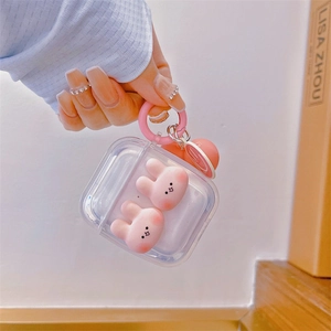 Close-up of clear AirPods case with pink bunny dolls and a smiling face pendant charm