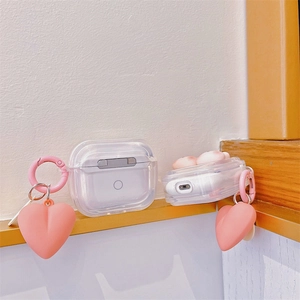 Transparent AirPods Pro case with pink heart pendant and silver ring clip on wood