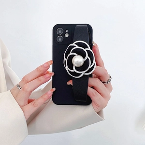 Detail of iPhone case featuring a black camellia flower wrist strap and a large pearl center