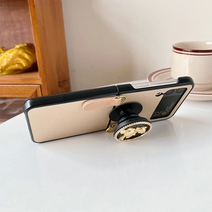 Samsung Galaxy Z Flip case with gold bear ring kickstand and leather hand strap detail