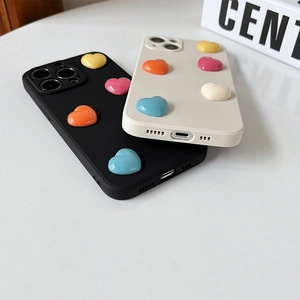 Dettaglio di cover per iPhone nere e crema con ornamenti colorati a cuore 3D in resina