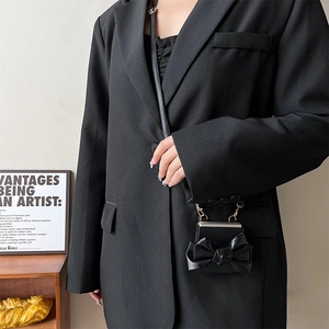 Detail of crossbody phone case with large bow and leather strap in black finish