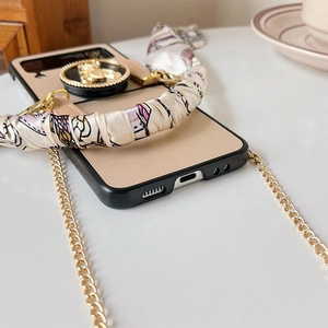 Detail view of foldable phone case with gold bear ring holder and floral ribbon handle