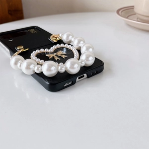 Detail of Galaxy Z Flip case with pearl heart, metal bow and elegant pearl chain strap