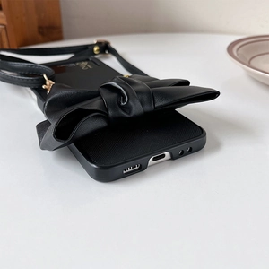 Detailed side view of black leather bow phone case with adjustable crossbody strap