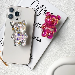 Close-up of glitter bear phone grips with 'Sweet' text on white smartphone