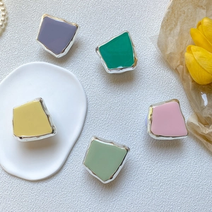 Macro detail of irregular geometric enamel pins with silver metal edges in pastel colors
