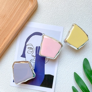 Macro detail of electroplated square phone grips in soft pastel pink, yellow, and purple