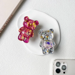 Close-up of sparkling sequin bear phone grips with Sweet text on white ceramic tray
