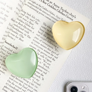 Détail des supports de téléphone en forme de cœur jaune et vert sur un magazine