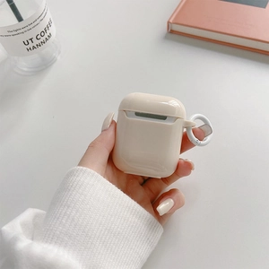 Close-up of cream silicone AirPods case with white ring hook in a cozy lifestyle setting