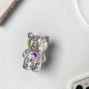 Detailed view of a transparent glitter bear phone stand with Sweet gold lettering