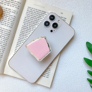 Pink geometric phone grip with silver metallic edge on smartphone over a book