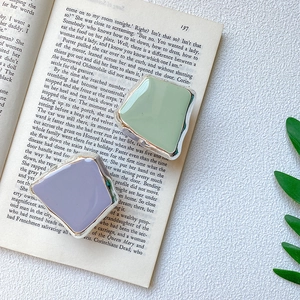 Detail of light green and lavender square enamel phone grips on a vintage book