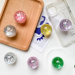 Close-up of glitter star and moon phone grips in various colors on a white background