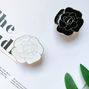 Close-up of black and white camellia flower phone grips with metallic plated edges