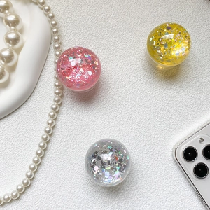 Close-up of sparkling heart and moon glitter inside a clear round phone grip