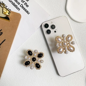 Close-up of vintage floral pop socket with rhinestones and pearls on a white desk