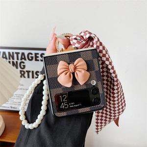 Detail of Z Flip folding phone case with vintage brown checkerboard, pink bow, and pearl strap