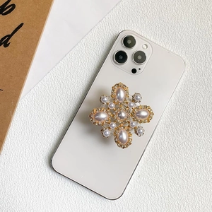 Macro view of luxury cross floral phone grip with pearls and rhinestones on a smartphone