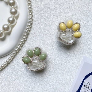 Close-up of cat paw phone grips with sparkling rhinestones and pearl bow details