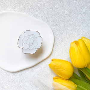 Detailed close-up of a white camellia flower phone socket grip on a ceramic tray
