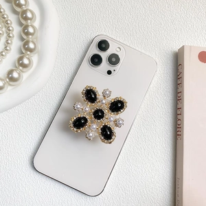 Luxury rhinestone phone grip with black gemstones and pearls on white phone case