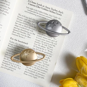 Detailed view of Saturn-shaped gold and silver metal phone grips on a magazine surface
