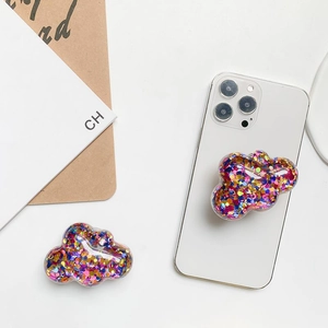 Detail view of two cloud-shaped glitter phone grips with colorful sequins on a smartphone