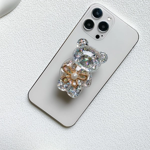 Close-up of glittery bear phone grip with golden flower and pearl embellishments