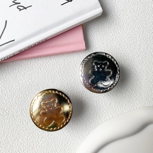 Close-up of gold and silver bear-shaped metal phone sockets with lace edges on desk