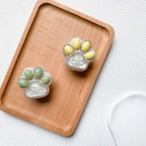 Detail of cat claw phone grips with rhinestones and pearl bow on a wooden tray