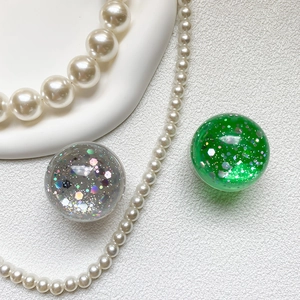 Detail view of round glitter phone grips in sparkling silver and emerald green resin finish