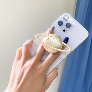 Detail of champagne gold planet phone socket grip with star pattern on white smartphone
