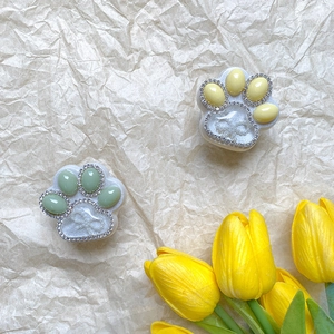 Detail of cat paw phone grips in mint green and yellow with rhinestones and bows