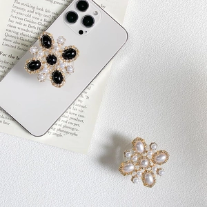 Close-up of vintage flower phone grips with pearl inlay on a white smartphone back