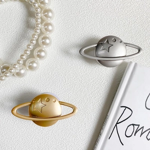 Close-up of gold and silver planetary phone stands with metallic ring and star patterns