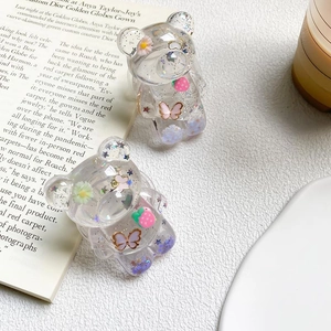 Detail of transparent resin bear phone grip with glitter, daisies and strawberry glitters