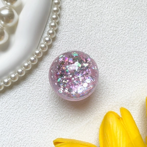 Close-up of pink glitter phone grip featuring colorful stars and moon sequins inside
