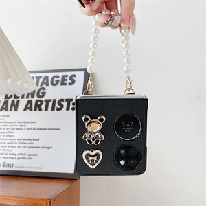 Detail of black leather folding case with large pearl strap and golden bear charm