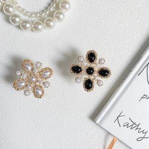 Close-up of elegant cross flower earrings with white pearls and black gemstones