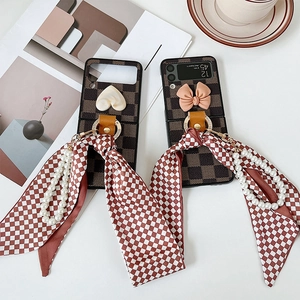 Detail of Galaxy Z Flip case featuring checkered pattern with pearl strap and bow ribbon
