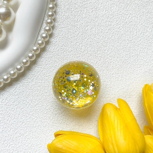 Macro shot of yellow crystal phone grip filled with colorful star and hexagon glitter