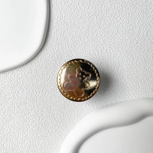 Detail of a round gold metallic phone grip featuring a relief bear and wave edge design