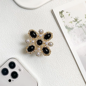 Baroque phone grip with black gems, pearls and crystals on a minimalist background